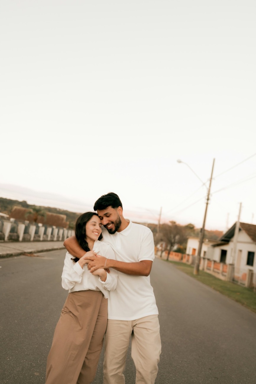 Casal abraçado e sorrindo em uma rua tranquila