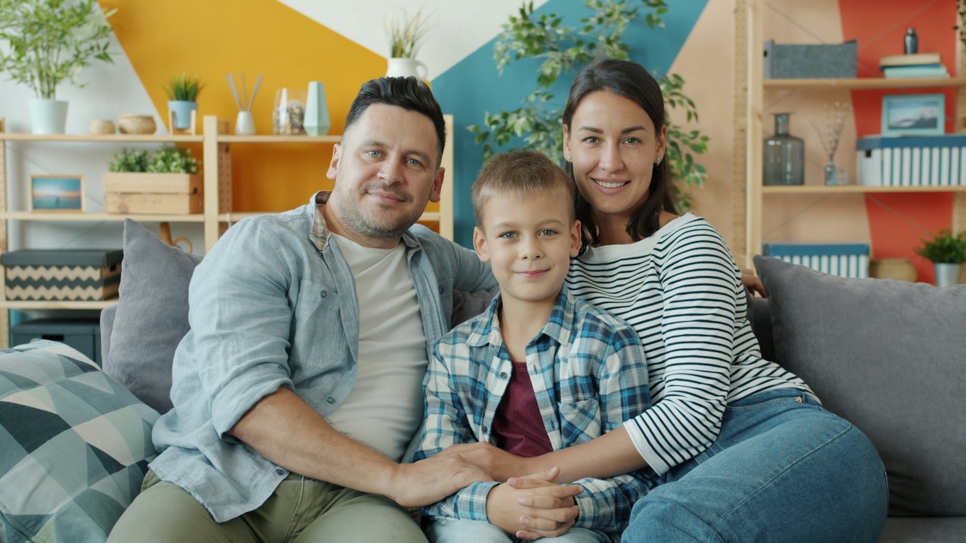 Família sorrindo no sofá de casa